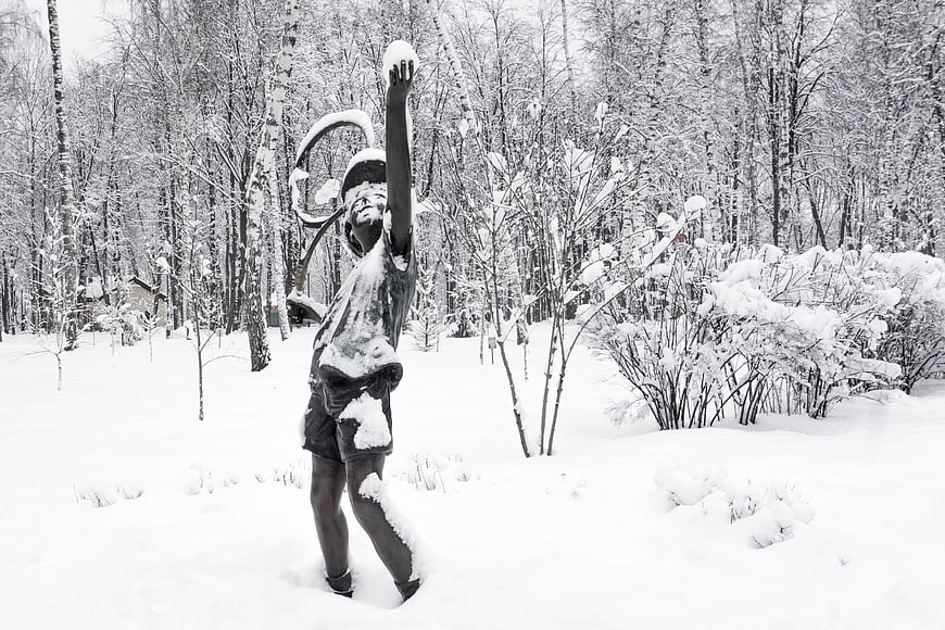 Snow-covered statue of a boy in a winter park