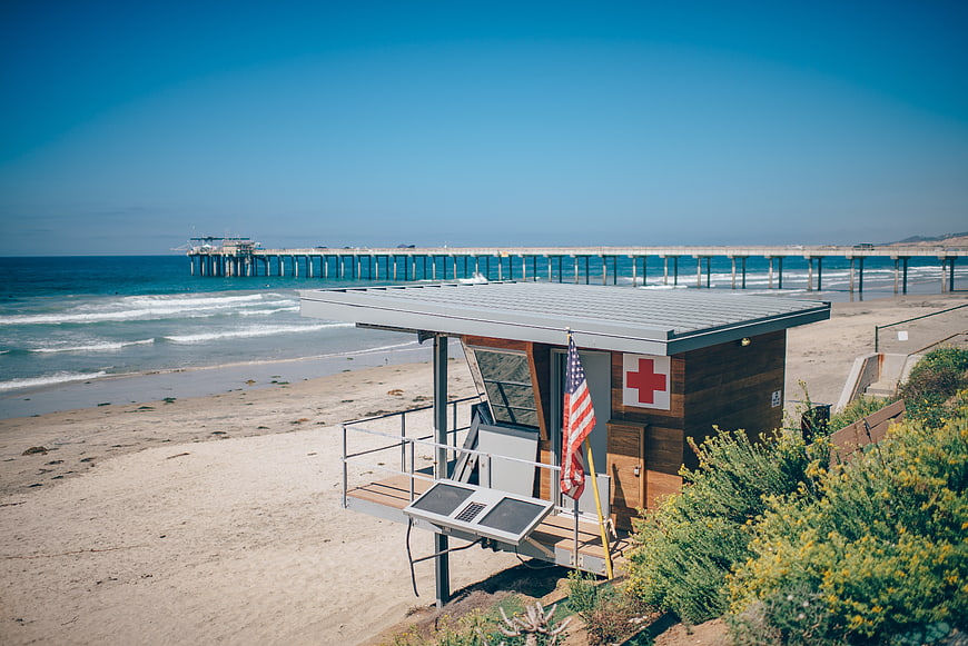 Lifeguard tower on sandy beach with pier and ocean view