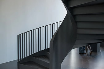 Modern black spiral staircase with people walking underneath