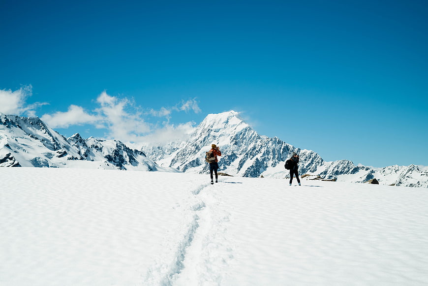 Hikers trekking on snowy mountain glacier with blue sky