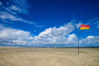 Red and yellow beach safety flag on sandy shore