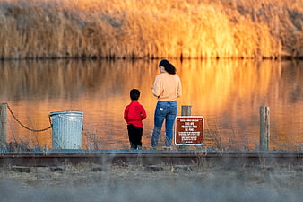 Mother and son standing by a pond at golden hour