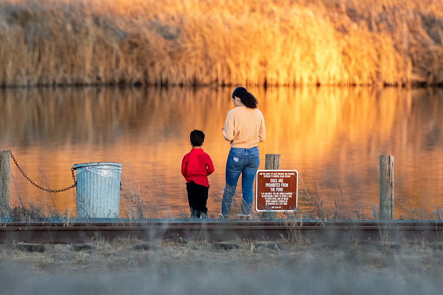 Mother and son standing by a pond at golden hour