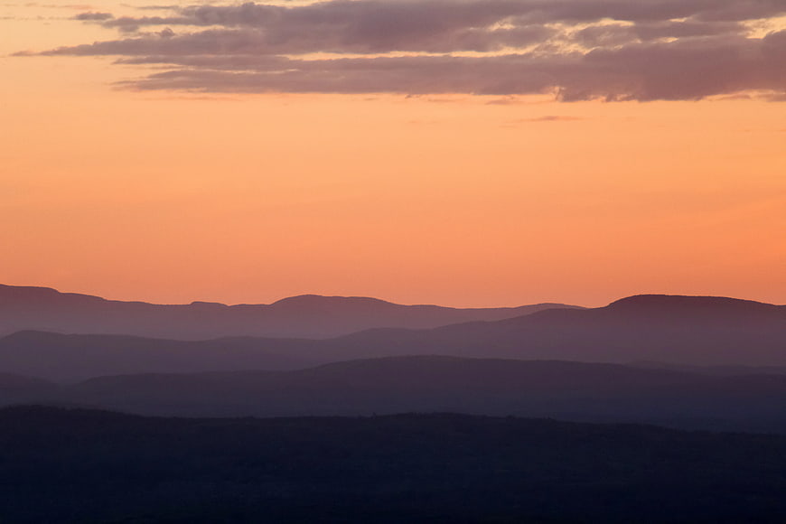Layered Mountain Silhouettes at Sunset with Orange Sky