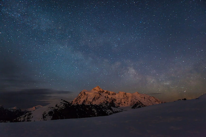 Snowy Mountain Peaks Under Starry Night Sky