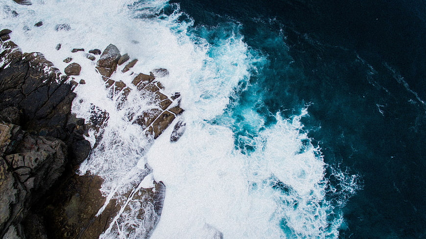 Aerial View of Turquoise Waves Crashing on Rocky Coastline