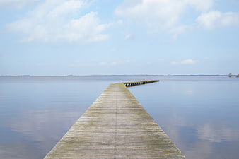 Long wooden pier extending into calm blue water