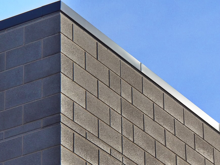 Modern gray concrete block building corner against blue sky