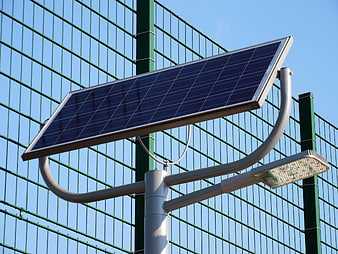 Solar Powered Street Light With Photovoltaic Panel Against Green Fence