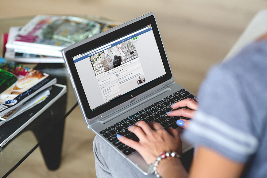 Woman typing on laptop browsing interior design blog