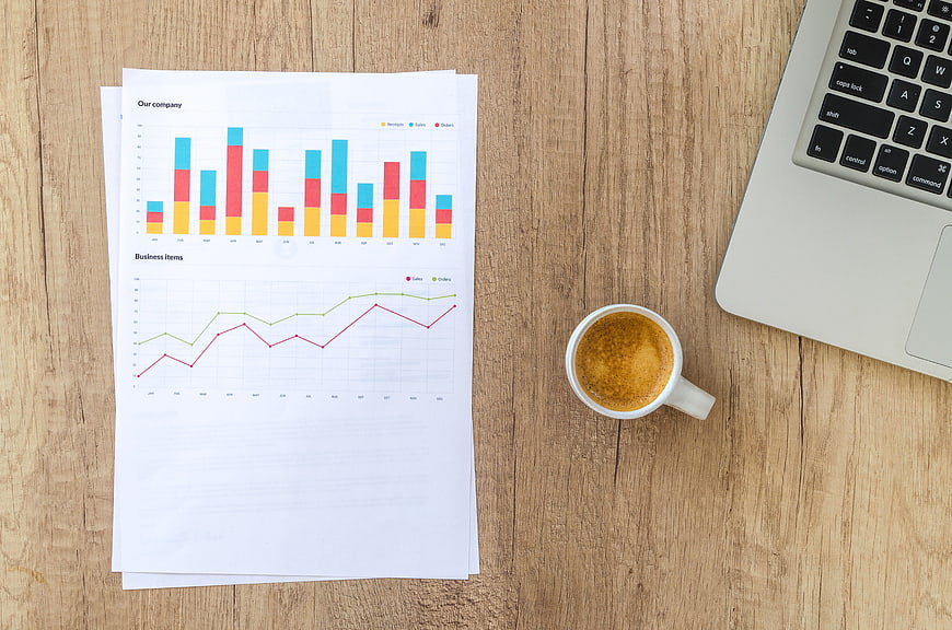 Business financial charts and coffee on wooden desk