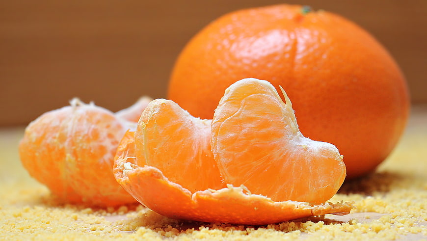 Fresh peeled tangerine segments with whole fruit on crumbs
