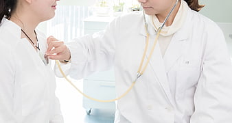 Doctor examining patient with stethoscope in clinic