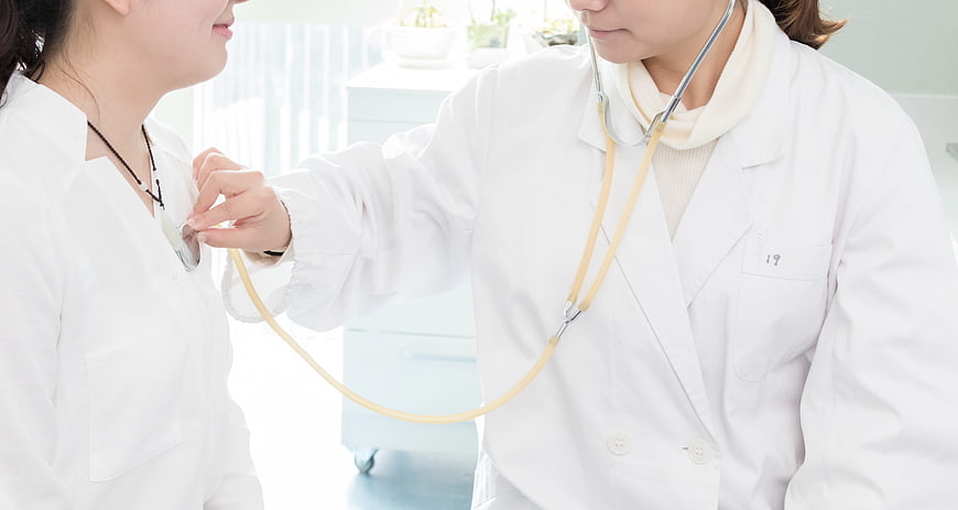 Doctor examining patient with stethoscope in clinic