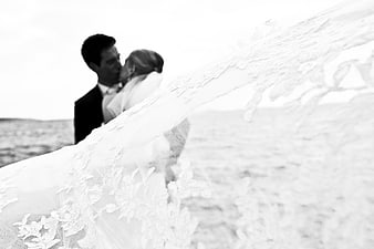 Black and white wedding couple kissing behind flowing lace veil