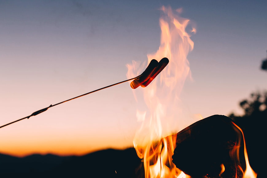 Roasting Hot Dogs Over Campfire at Sunset