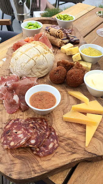 Rustic charcuterie board with salami, cheese, bread, and bitterballen