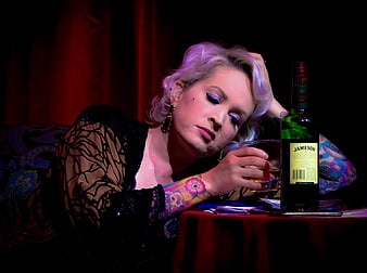 Tattooed Woman Drinking Whiskey in Dark Bar Setting