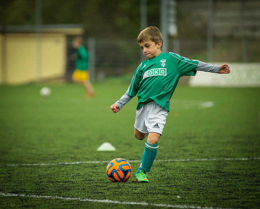 Young boy playing soccer on green field