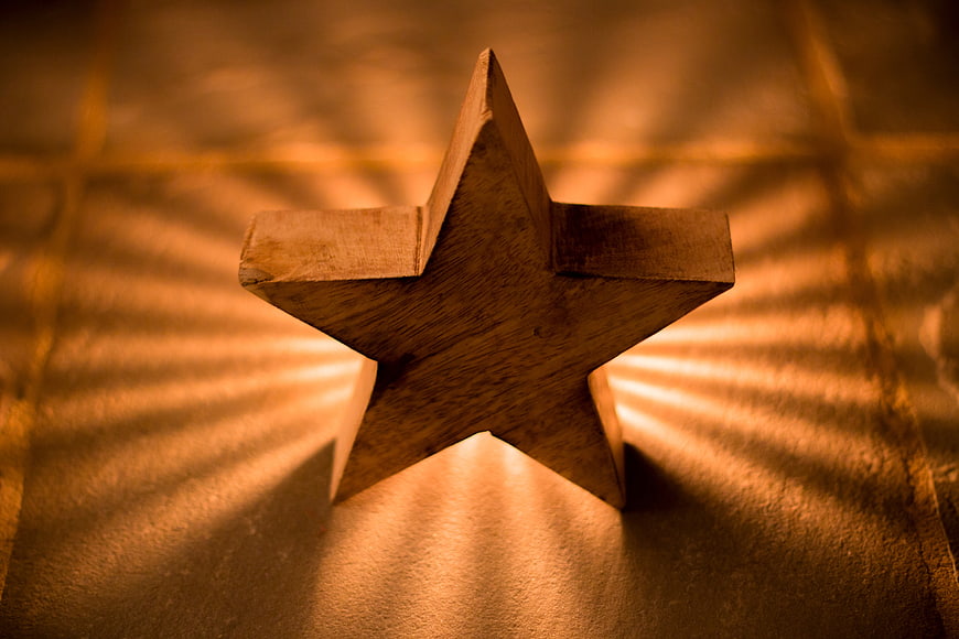 Wooden Star with Radiating Light Rays on Textured Surface