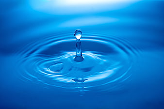Blue water droplet splash with ripples on calm surface