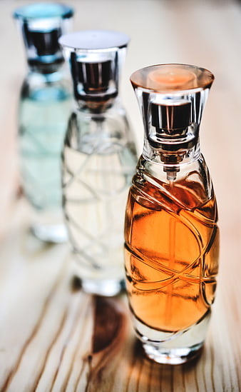 Three elegant perfume bottles on wooden surface