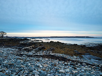 Tranquil Rocky Shoreline at Dusk with Blue Sky