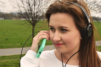 Young Woman Listening to Music with Headphones in Park