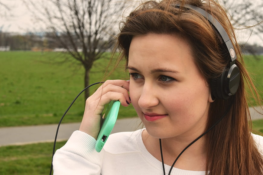 Young Woman Listening to Music with Headphones in Park