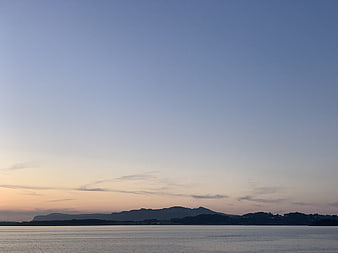 Serene Sunset Over Calm Water and Distant Mountains