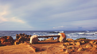Stone bench overlooking rocky ocean coastline with waves