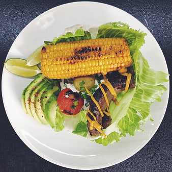 Overhead shot of grilled corn, steak, and avocado salad
