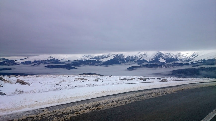 Snowy mountain road with foggy valley and overcast sky