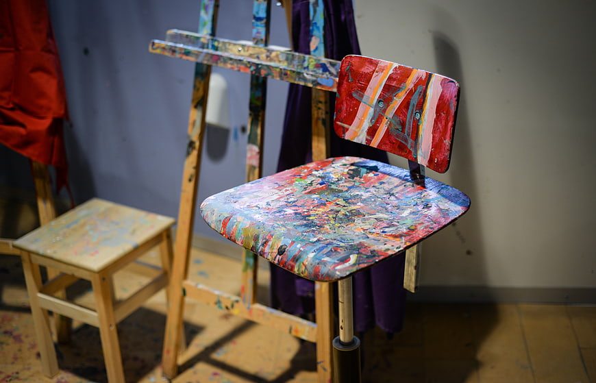 Paint-splattered wooden stool in artist studio