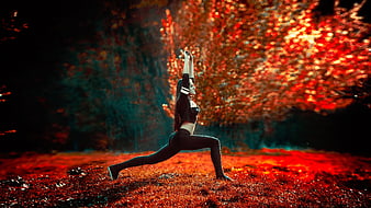 Woman stretching in autumn forest with vibrant red leaves