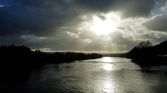Dramatic Sun Rays Breaking Through Clouds Over a River