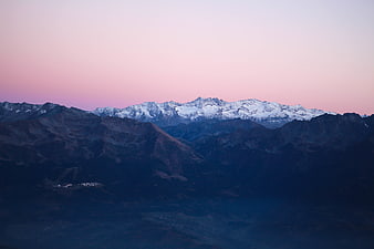 Snow-capped mountain range at twilight with pink sky