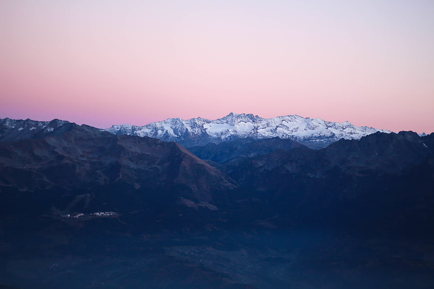 Snow-capped mountain range at twilight with pink sky