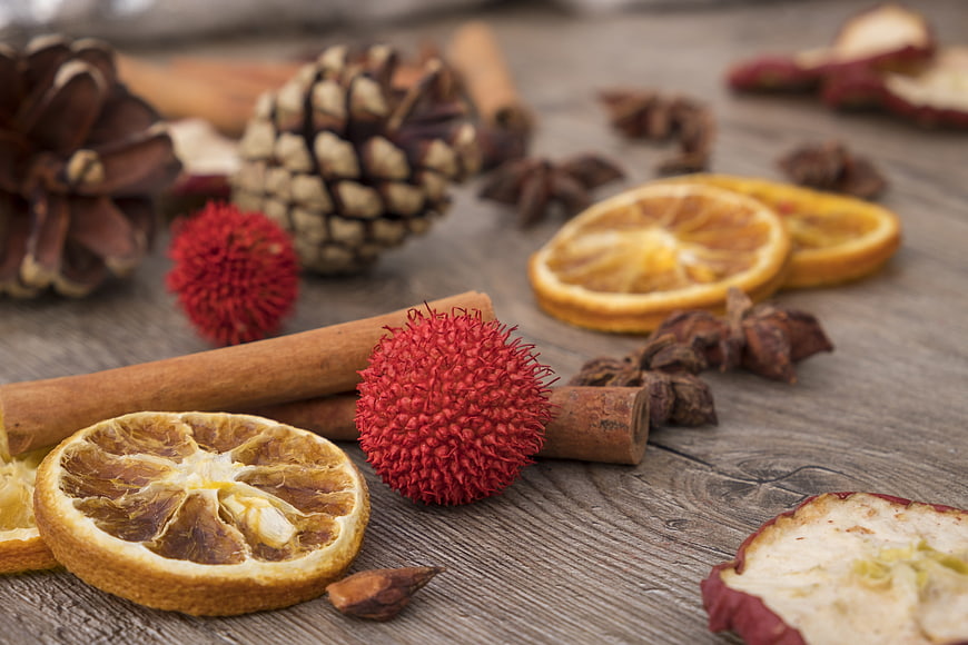 Dried orange slices, cinnamon, and pinecones on rustic wood