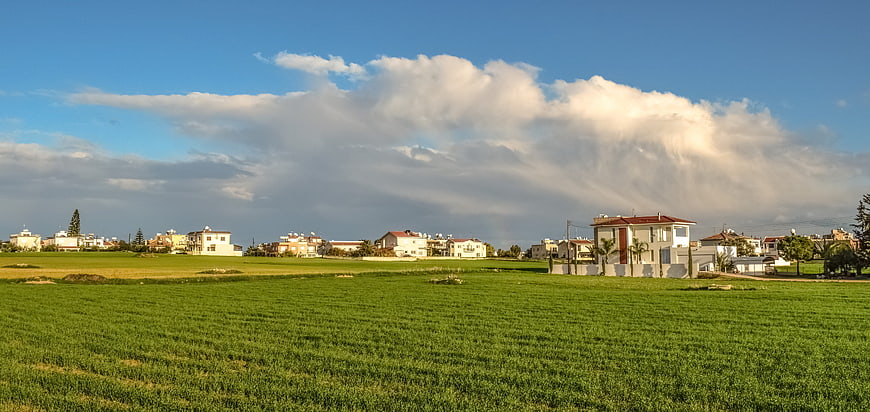 Green agricultural field with houses and dramatic storm clouds