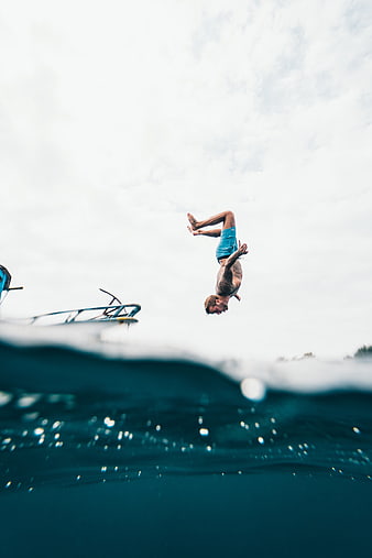 Man performing a backflip into the ocean from a boat