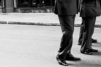 Black and white photo of men in suits standing on street