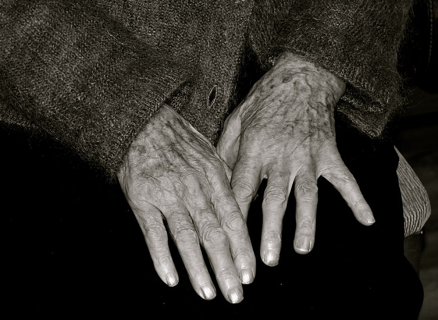 Close-up of elderly woman's wrinkled hands resting on lap