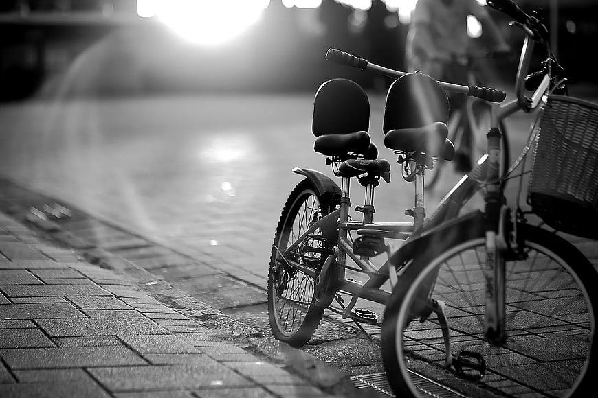Black and White Tandem Bicycle on Wet Sidewalk at Night