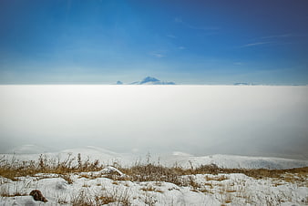 Snowy mountain peak above sea of clouds winter landscape