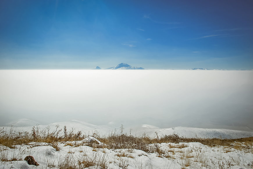 Snowy mountain peak above sea of clouds winter landscape