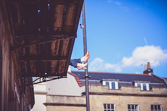 Bare feet dangling from wooden balcony against blue sky