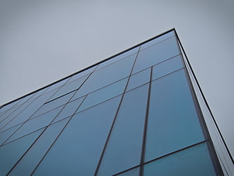 Low angle view of modern glass building facade against gray sky