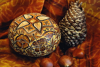 Decorated gourd bowl with pinecone and chestnuts on fabric