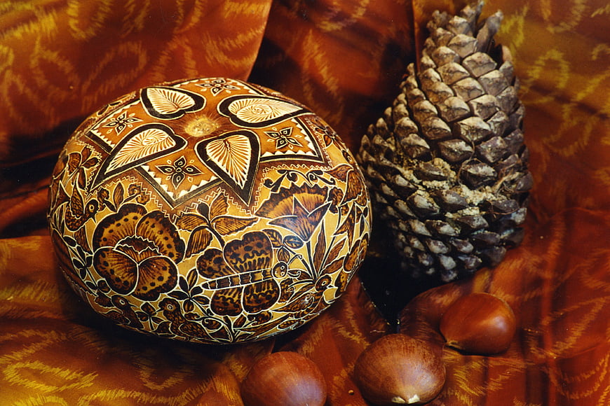 Decorated gourd bowl with pinecone and chestnuts on fabric